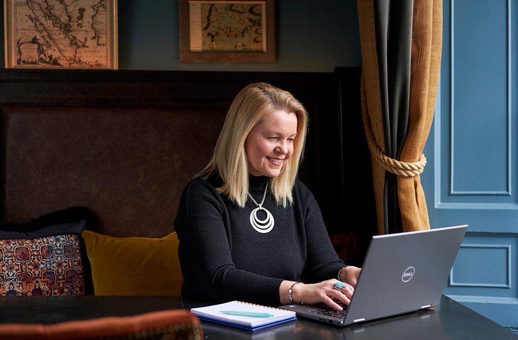 Dympna Mckenna sitting at her laptop and writing.