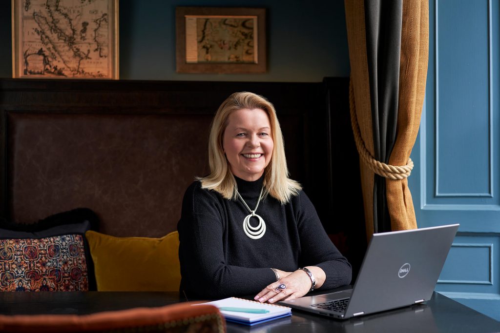 Dympna Mckenna sitting at a desk with her laptop